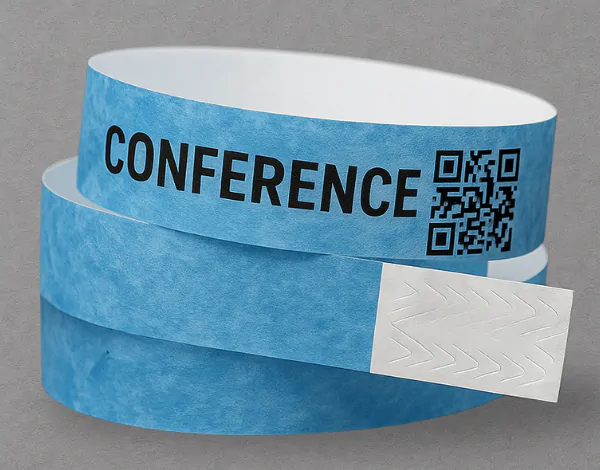 Blue Tyvek wristband with &ldquo;CONFERENCE&rdquo; text and a printed QR code, showing tamper-evident adhesive and single-use closure for secure event access