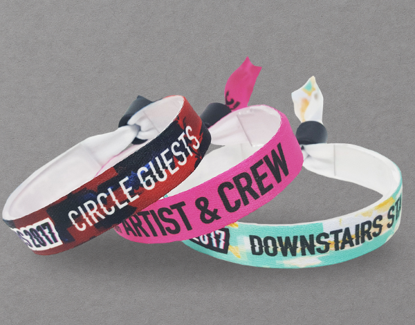 Three fabric wristbands with printed labels like &ldquo;CIRCLE GUESTS&rdquo; and &ldquo;ARTIST & CREW,&rdquo; featuring barrel locks for secure, tamper-evident use at events