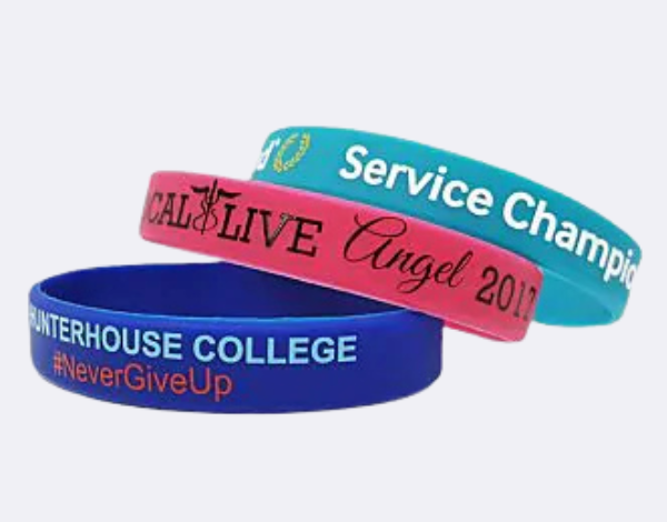 Three silicone wristbands in blue, pink, and teal with printed slogans and branding, illustrating long-lasting wristbands for promotions or charity events