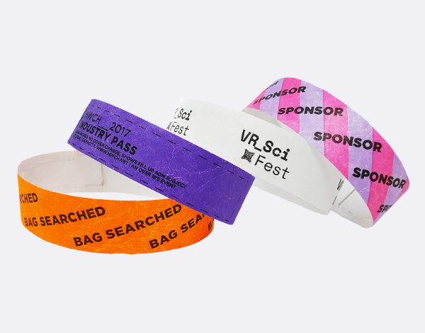 Assorted Tyvek wristbands in orange, purple, and white with printed event labels, representing a low-cost option for single-day events in the UK